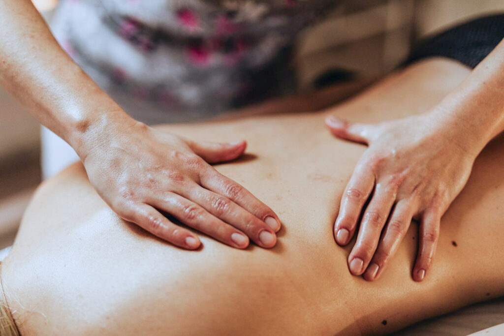Tuina-Massage 2 Therapeutin massiert den Rücken einer Person mit beiden Händen